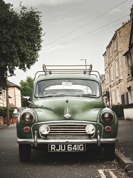 A green Morris Minor on a village street